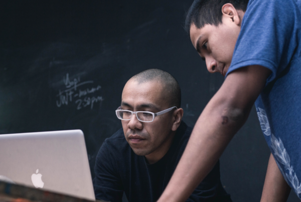 Two people looking at a laptop in a classroom