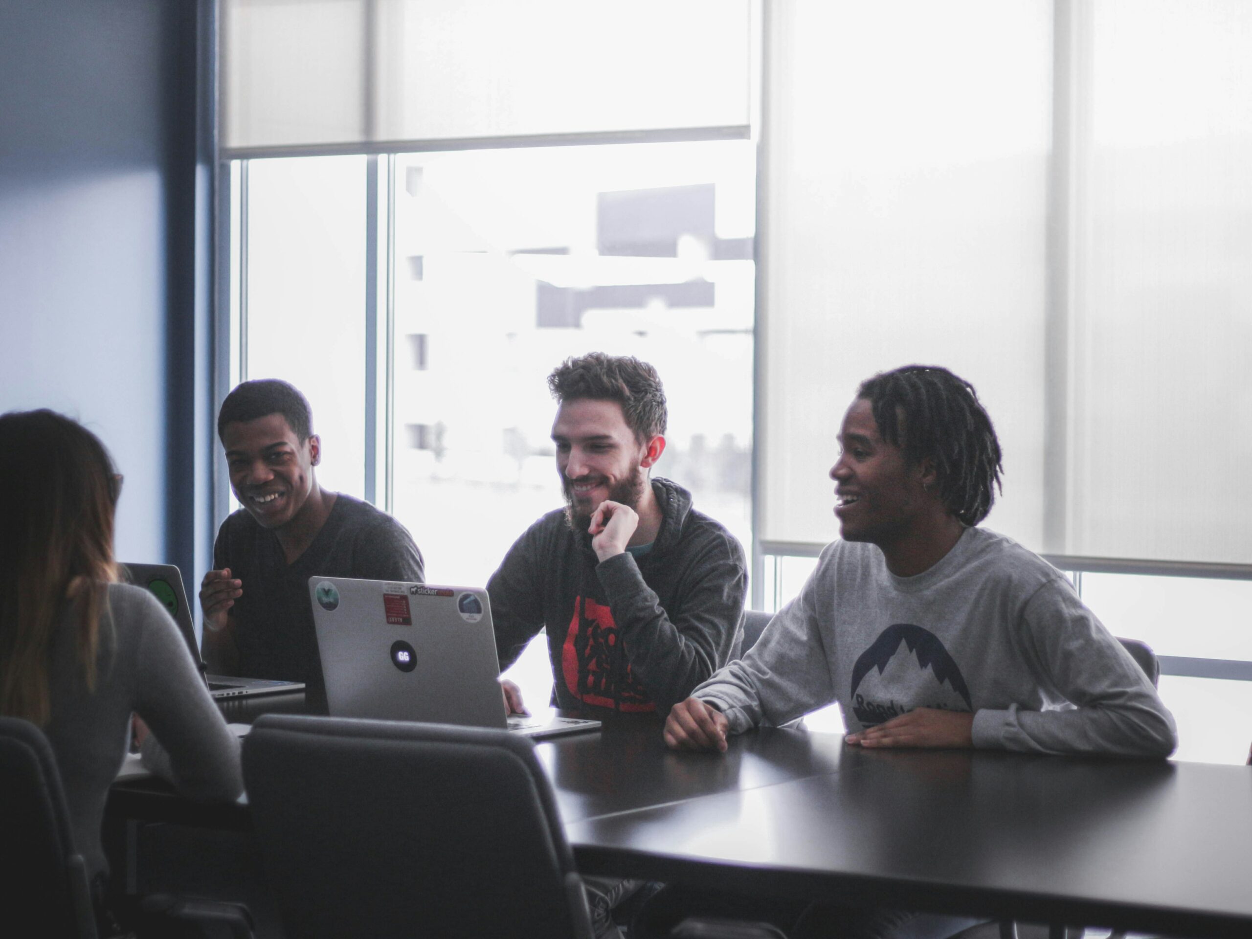 Colleagues talking and sitting around a laptop in a meeting room