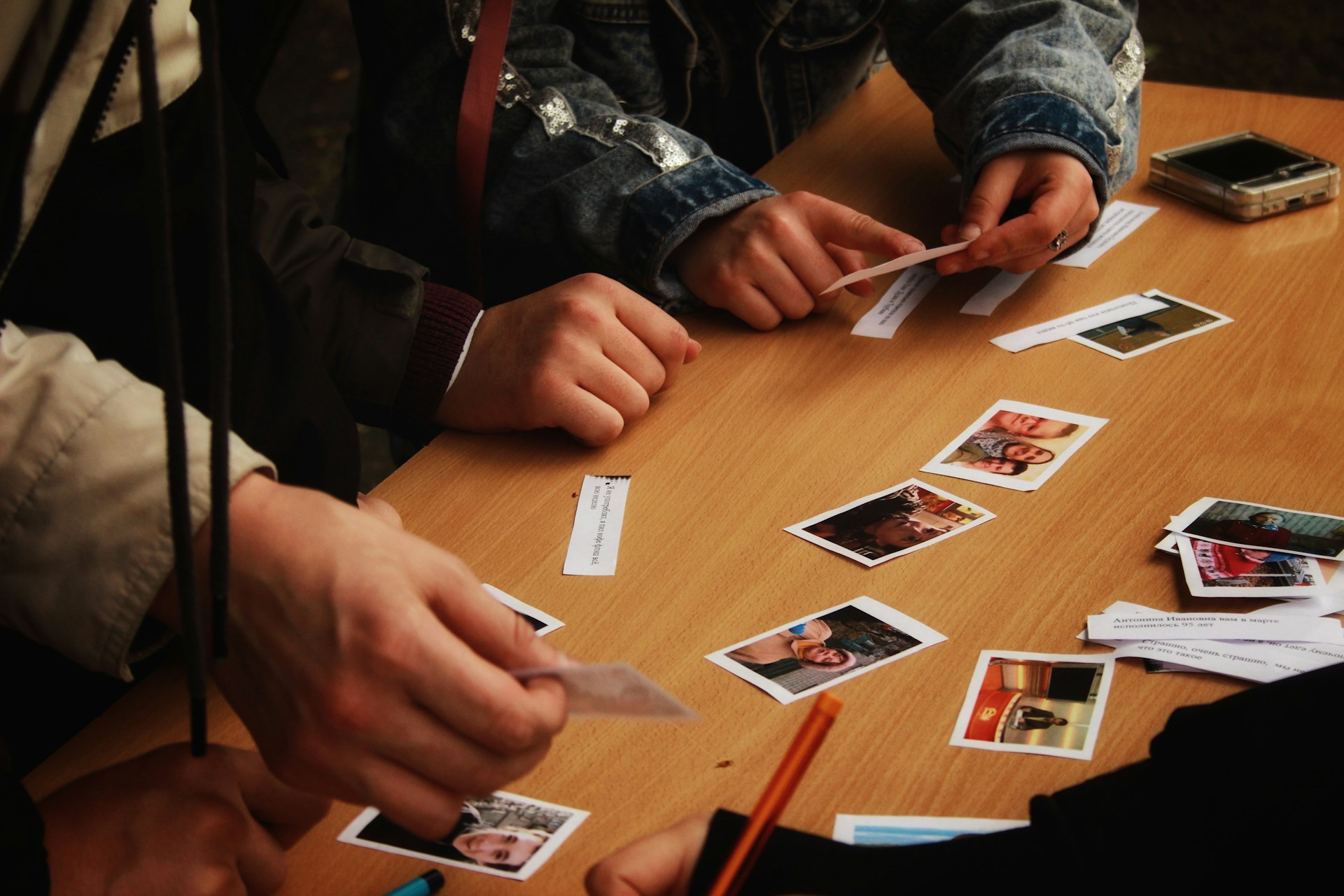 Students organising and discussing photos of people on a classroom desk.