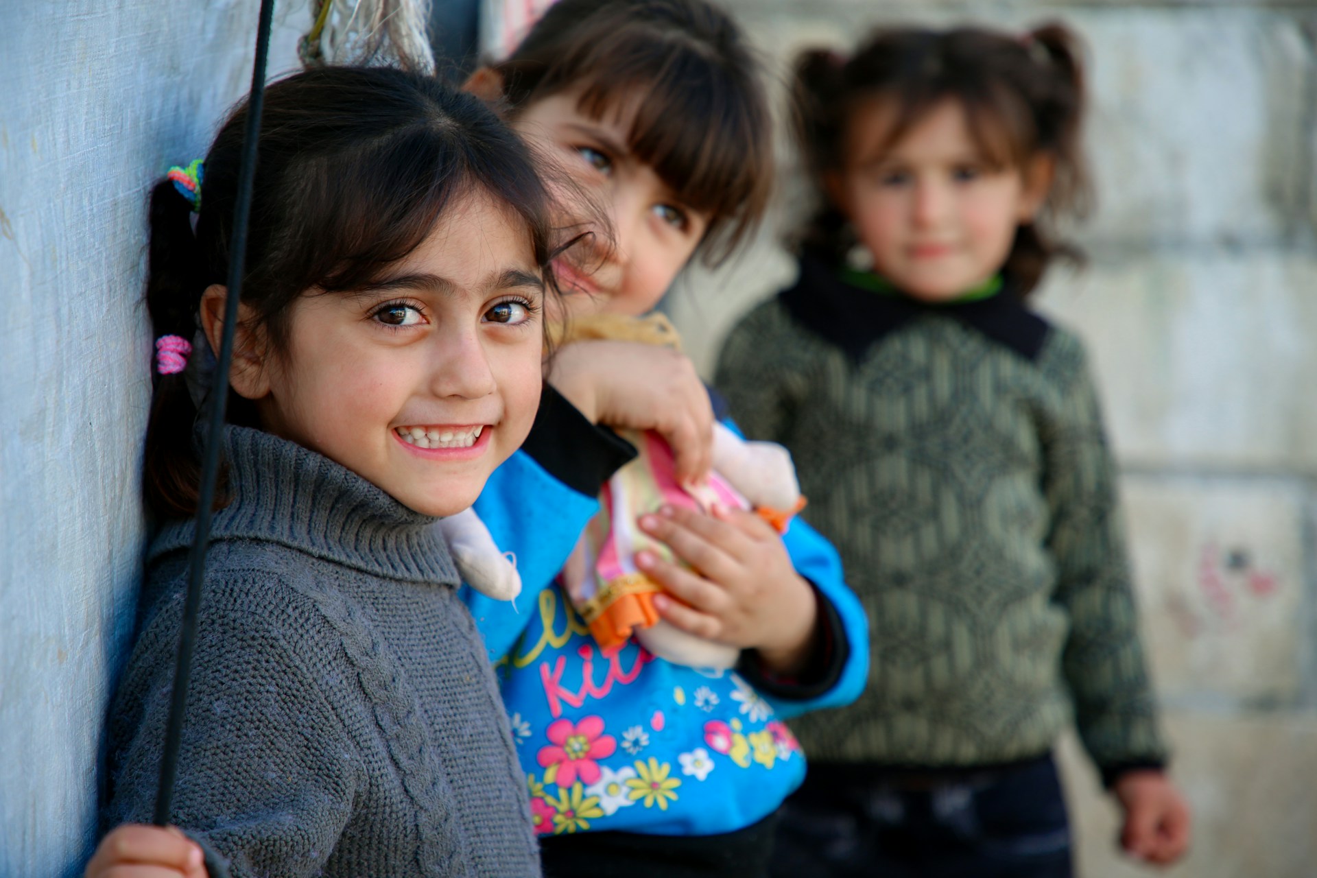 Three primary aged girls smiling and looking towards the camera.