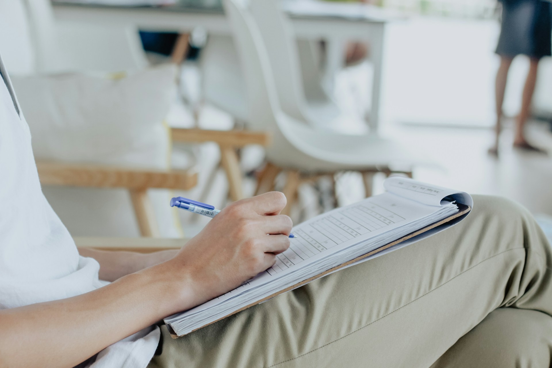 Person taking notes while sat in a modern classroom.